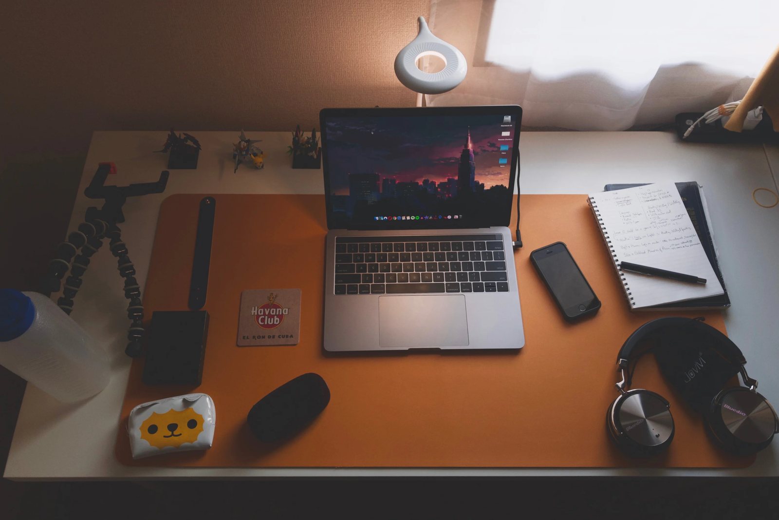 My home desk: laptop, handwritten notebook, and headphones in warm lamplight